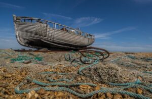 Derelict wooden fishing boat on the shingle beach of Dungeness in Kent, England